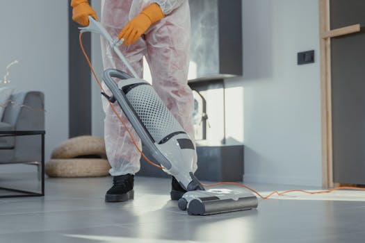 A person in protective attire cleaning a modern room with a vacuum. Bright and tidy atmosphere.