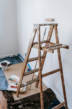 A room undergoing renovation with paint roller and ladder for interior design.